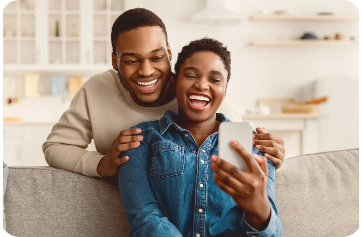 Smiling couple on a sofa looking at a phone