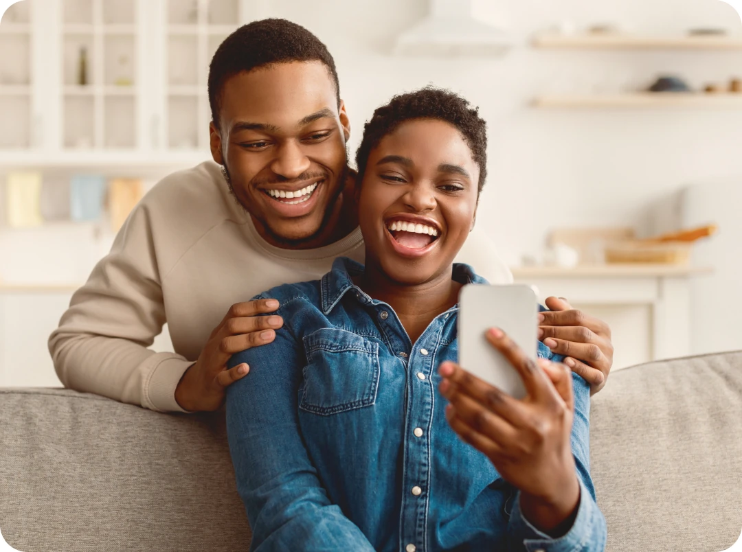 Smiling couple on a sofa looking at a phone